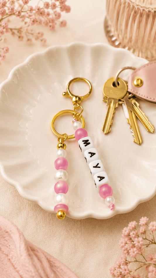 Elegant silicone bag charm with pearl and soft pink beads and gold-tone hardware on a soft cream background.