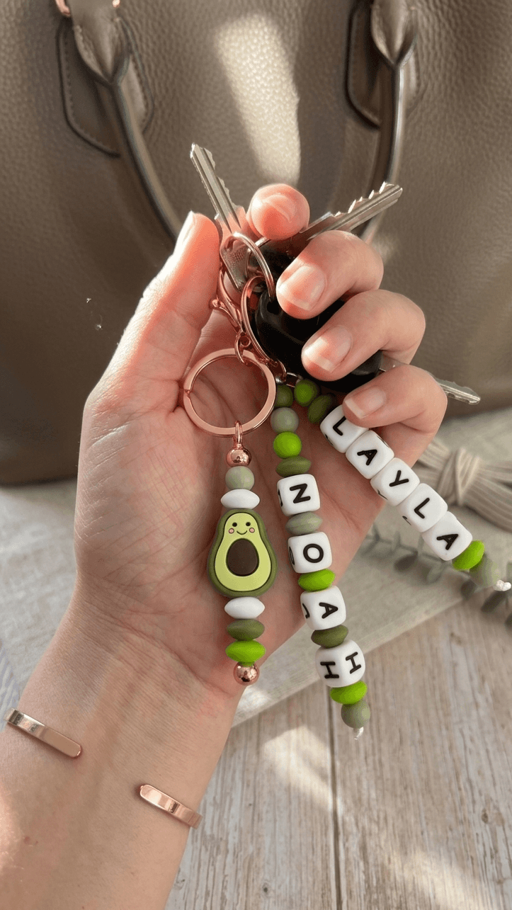 Personalised silicone bead name charm in elegant colours, clipped securely onto a stylish bag.