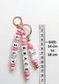 A stylish and practical baby accessory: a personalized name charm attached to a diaper bag on a stroller. The product combines identity and aesthetic design, perfectly matching modern nursery and parenting gear.