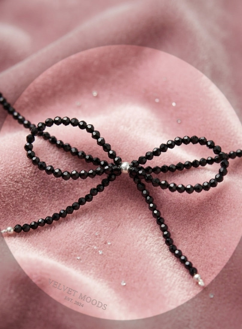 Close up of a trendy coquette bow made of 3mm faceted black tourmaline beads with solid silver accents.