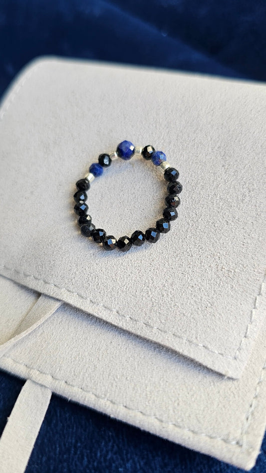 Three handmade elastic gemstone rings with Lapis Lazuli, Black Tourmaline and Moonstone beads, featuring gold and silver accents on a minimalist background.