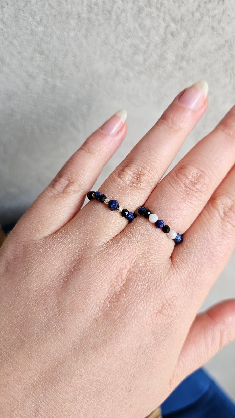 Person wearing stackable Lapis Lazuli and Black Tourmaline elastic rings for a minimalist boho jewelry look.