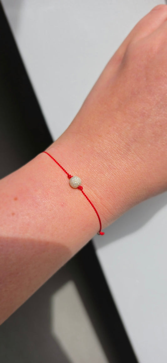 Handmade red string protection bracelet with a sparkling 6mm diamond-cut 925 sterling silver bead on a woman's wrist.