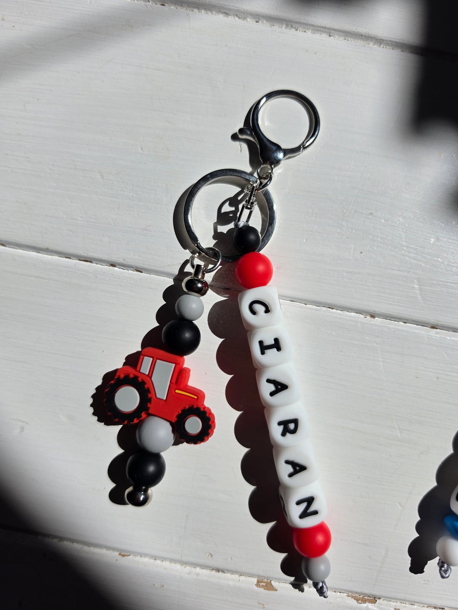 Close-up of a handmade personalised charm showing letter beads, soft-touch silicone beads, and a premium rose gold metal attachment.