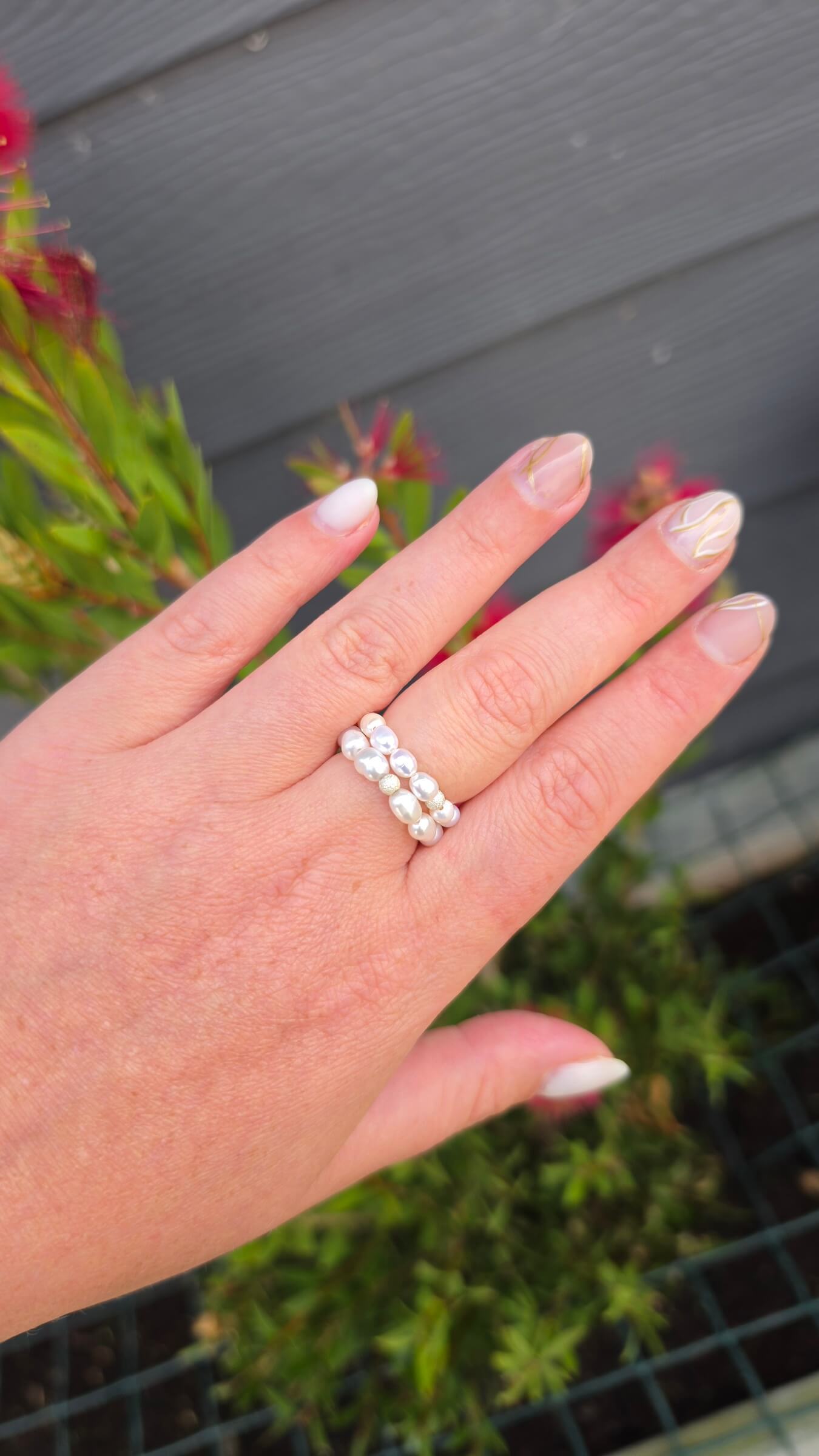 A stack of two delicate rice pearl elastic rings in sizes 3-4mm and 4-5mm on a model's finger, creating a beautiful, cascading luxury jewellery effect.