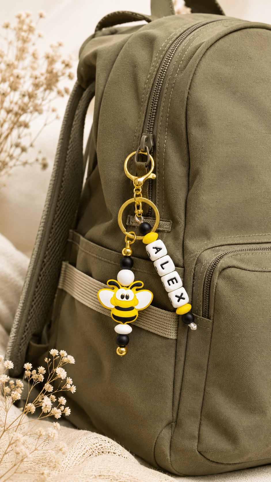 Personalised children's bee keyring attached to a black sports bag, featuring name beads, gold clasp and colourful silicone beads. A fun personalised accessory for school bags, PE bags, lunch bags and sports bags.