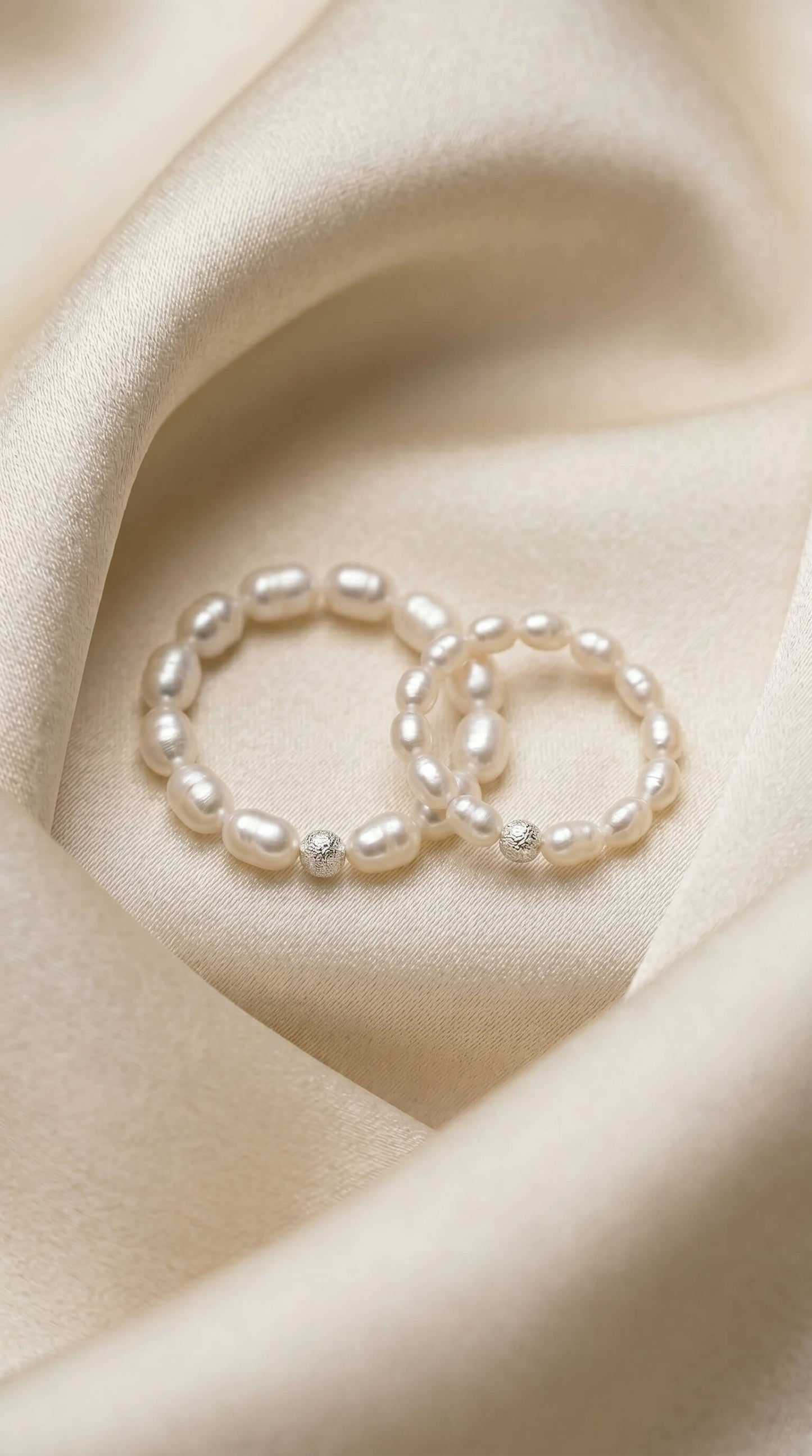Macro photograph of natural freshwater rice pearls with a deep satin lustre, threaded on a durable stretch cord next to a diamond-cut sterling silver bead.