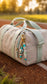 Turquoise and mint beaded keyring with personalised letter beads displayed on a neutral sports duffel bag in an outdoor setting.
