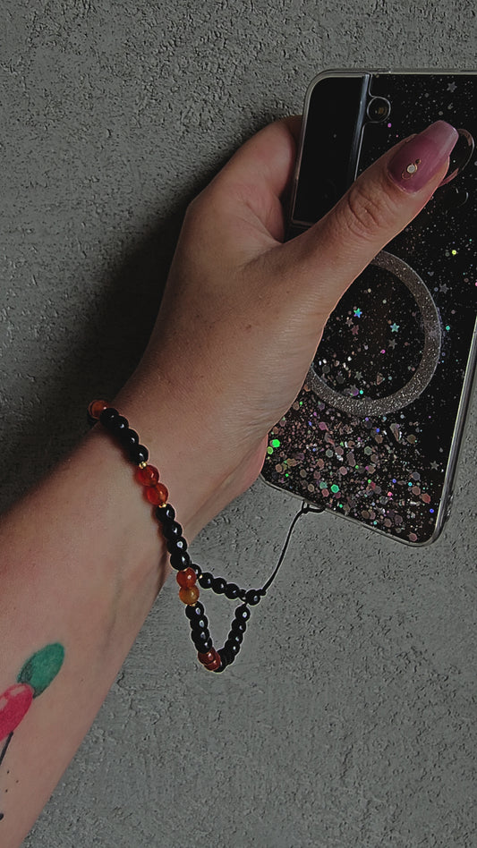Handmade crystal phone charm with black onyx and carnelian beads, gold accents and cord – protective, grounding and energising accessory.