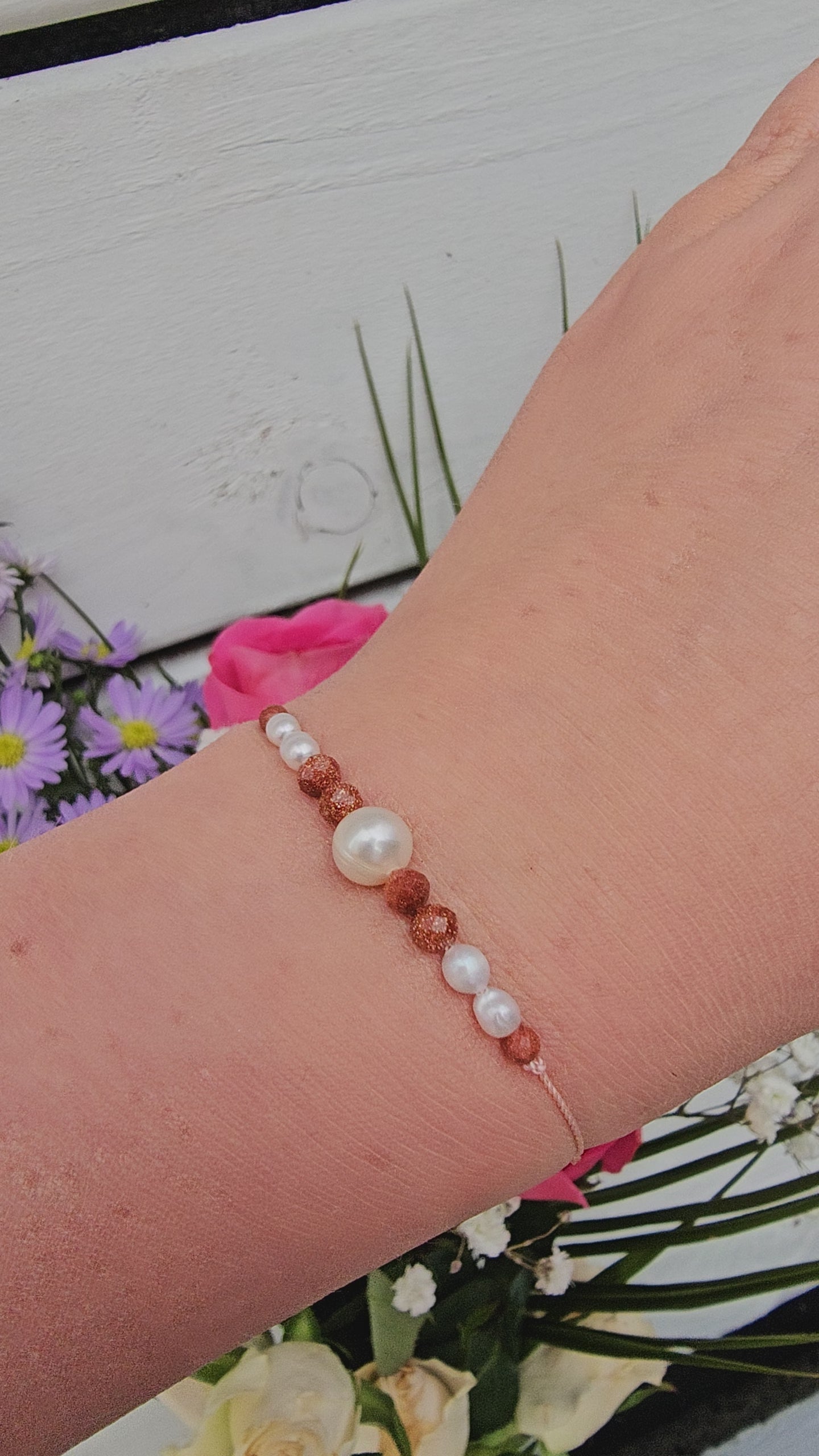 Handmade bracelet with white freshwater pearls and warm sandstone beads, styled on a woman's wrist. handmade in Ireland , Irish jewellery 
