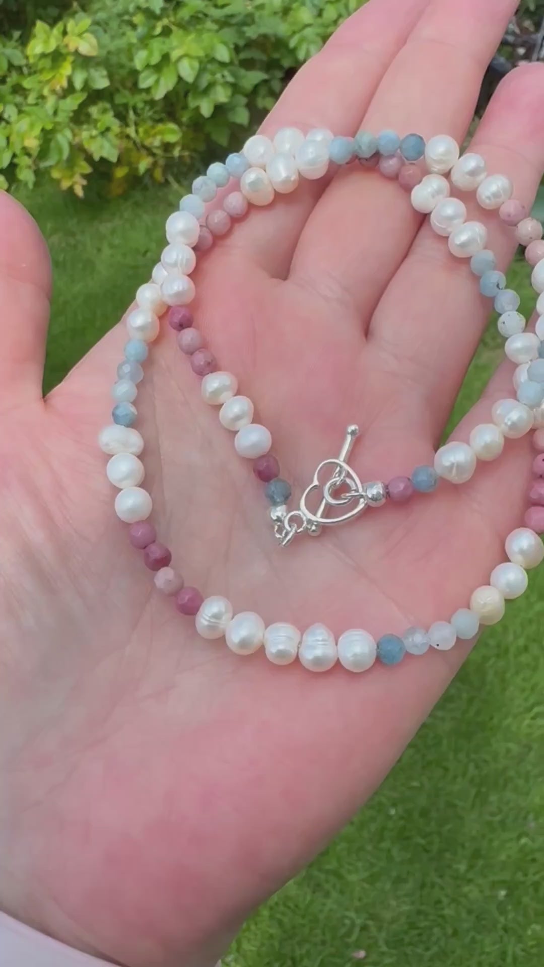 Close-up of handmade choker necklace with freshwater pearls, aquamarine and rhodonite gemstones, finished with 925 sterling silver heart toggle clasp. Comes in velvet pouch with silver cleaning cloth. Irish handmade gift-ready jewellery.